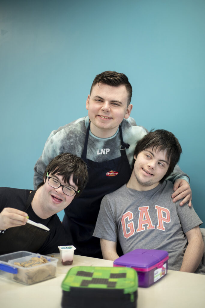 Three young men pictured at a table smiling